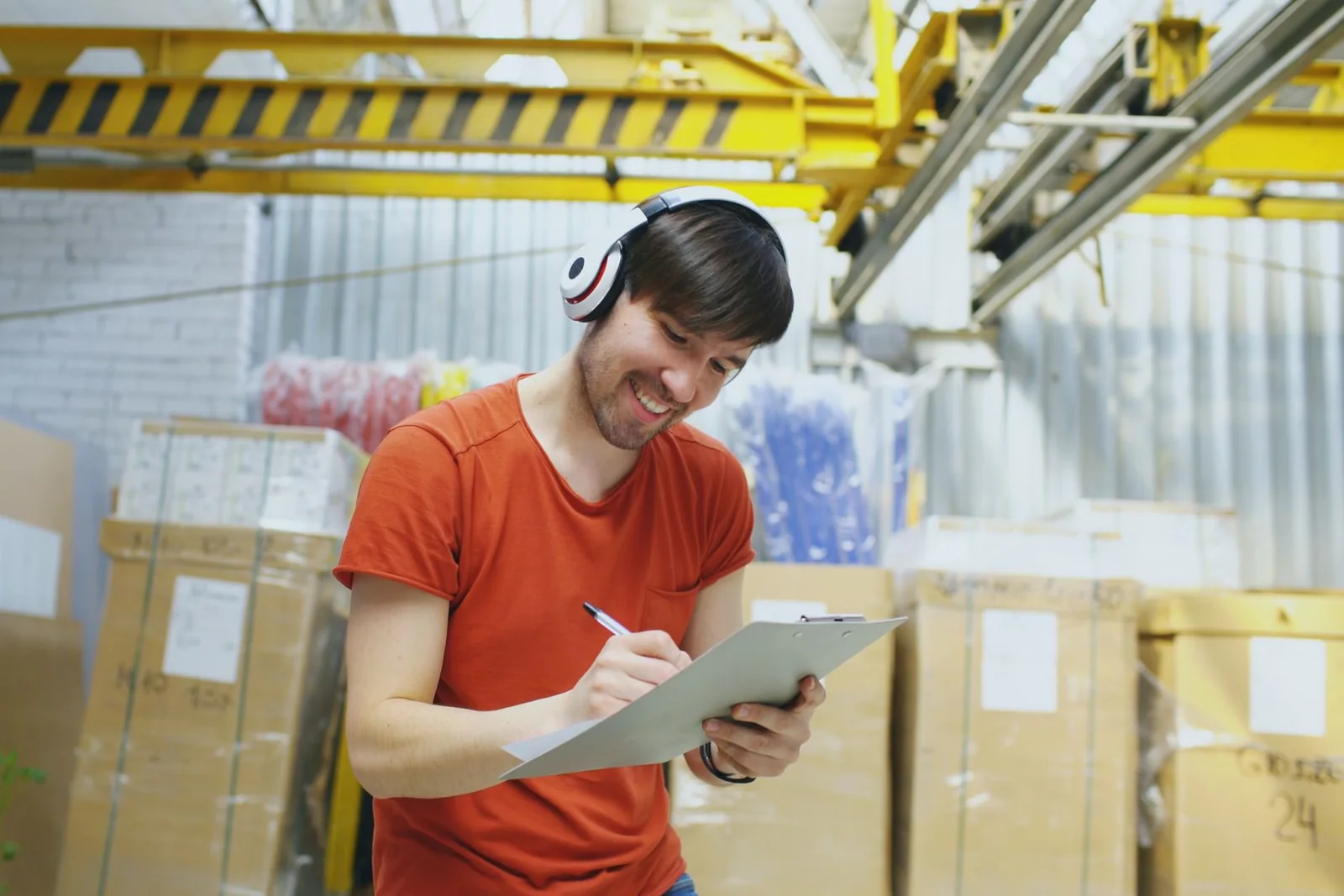 Warehouse quality worker recording inspection information on a clipboard.