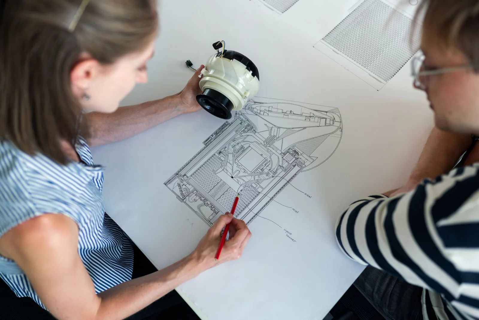 Engineers collaborating over a technical product drawing