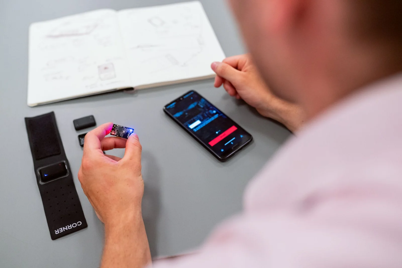 Engineer testing a connected wearable prototype with a smartphone